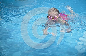 Pretty young girl swimming outdoors in a pool