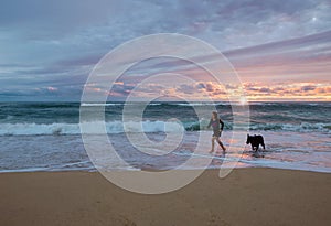 pretty young girl walking with her dog on the beach in the evening