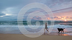 pretty young girl walking with her dog on the beach in the evening