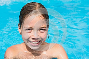 Pretty young girl in the water, kid in swimming pool is smiling