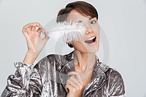 Pretty young girl wearing pajamas holding a feather