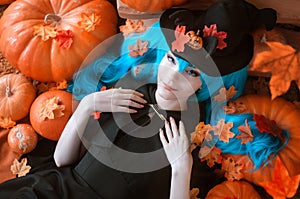 Pretty young girl witch halloween costume dressed in black with pumpkins