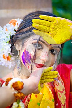 Pretty young indian girl showing colourful palm and celebrating Holi with colour splash, popular hindu festival celebrated across