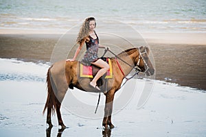 Pretty young lady riding a horse on the beach background of the sea