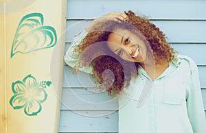 Pretty young lady smiling and leaning on surfboard