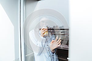 Pretty young lady standing at home looking at window