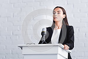 pretty young lecturer suffering from fear of public speaking while standing on podium tribune.