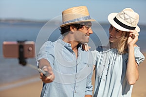 pretty young loving couple taking selfie together on sea beach