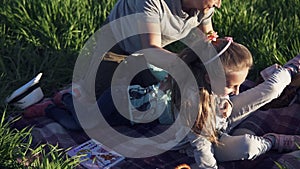 Pretty young man in park with his little children having fun. Playing with girls. They lie on the grass, laugh, their