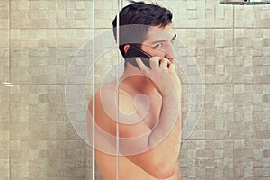 Pretty young man is talking by mobile in bathroom