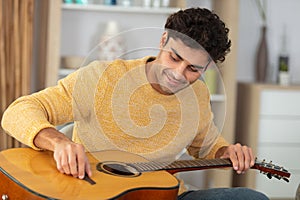 pretty young man tuning guitar