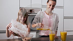 Pretty young mother and her daughter preparing breakfast in the kitchen at home