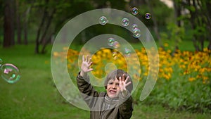 Pretty young mother with her a very cute young son happily blow bubbles outdoors in summer. slow-motion