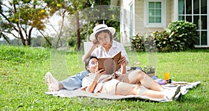 Pretty young mother reading book with her daughter on backyard