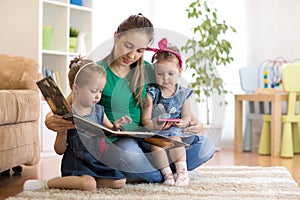 Pretty young mother reading a book to her daughters