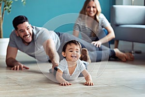 Pretty young parents playing with baby son while sitting on the floor at home