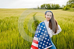 Pretty young pre-teen girl in field holding American flag.