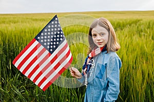 Pretty young pre-teen girl in field holding American flag.