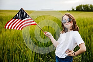 Pretty young pre-teen girl in field holding American flag