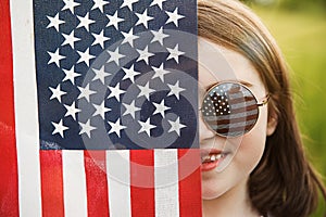 Pretty young pre-teen girl in field holding American flag