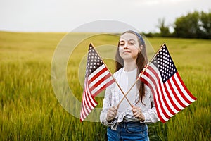 Pretty young pre-teen girl in field holding American flag