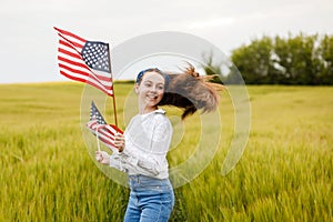 Pretty young pre-teen girl in field holding American flag