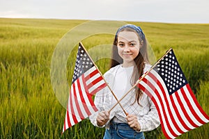 Pretty young pre-teen girl in field holding American flag