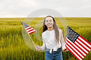 Pretty young pre-teen girl in field holding American flag