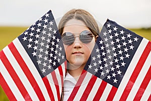 Pretty young pre-teen girl in field holding American flag