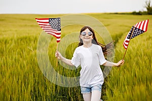 Pretty young pre-teen girl in field holding American flag