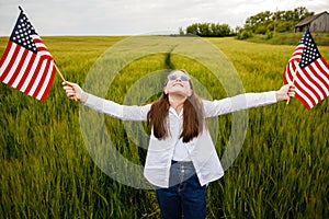 Pretty young pre-teen girl in field holding American flag