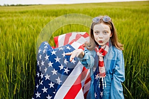 Pretty young pre-teen girl in field holding American flag