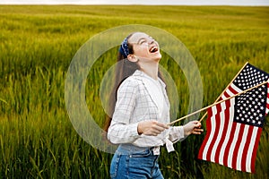 Pretty young pre-teen girl in field holding American flag