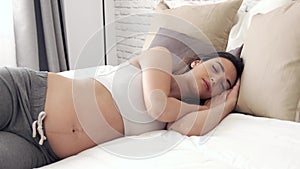 Pretty young pregnant woman sleeping in the bed at home. Peace and calm concept