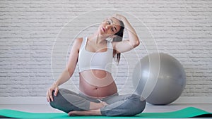 Pretty young pregnant woman stretching after doing pilates exercises in the pre childbirth classroom.