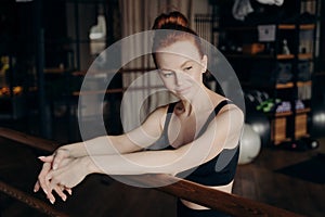 Pretty young red haired woman leaning on ballet barre