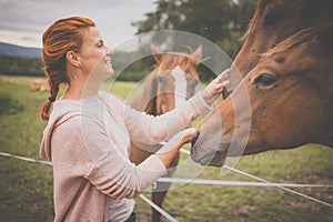 Pretty, young, redhead woman with her lovely horse