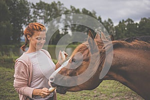 Pretty, young, redhead woman with her lovely horse