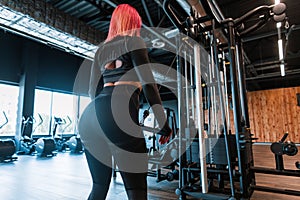 Pretty young sexy fitness woman with beautiful slim body doing exercises in the gym, back view