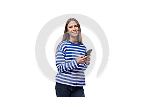 pretty young slim european model woman dressed in a blue sweater holding a smartphone in her hand on a white background