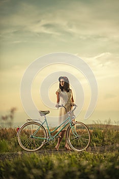 Pretty young smilling woman with retro bicycle in sunset on the road, vintage old times, girl in retro style on meadow