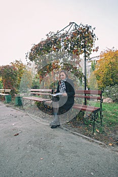 Pretty young student reading a book outside on the campus. The girl reading the book on the bench. hobbies, literature