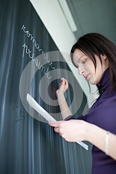 Pretty young student writing on the blackboard