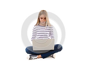 Pretty young teen girl sitting on the floor with crossed legs and using laptop,