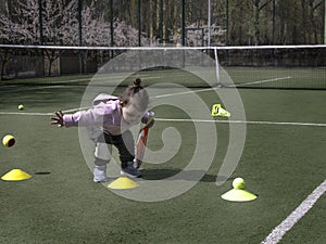 Pretty young tennis player with a racket on a tennis grass court, childrens tennis training