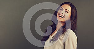 Pretty young toothy enjoying laughing woman with long brown healthy curly hair style in white shirt clothing. Closeup