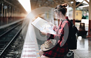 Pretty Young traveler woman looking on maps planning trip at public train station. Summer and travel lifestyle concept