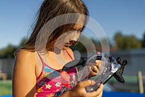 Pretty young well tanned girl in the swimming pool holding her diving mask and snorkel for scuba diving.