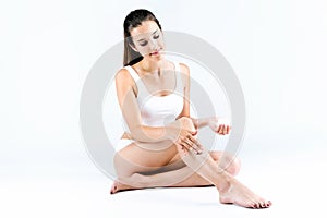 Pretty young woman applying body cream on legs. photo