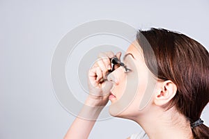 Pretty young woman applying mascara